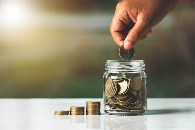 Person putting a coin inside a jar