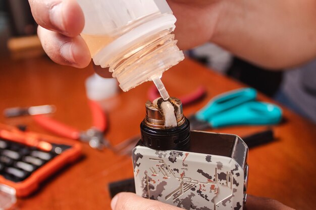 A person putting e-liquids to the vape - maintenance.