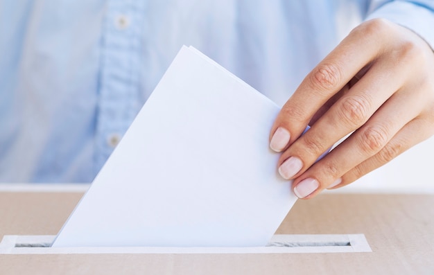 Photo person putting empty ballot in a box close-up