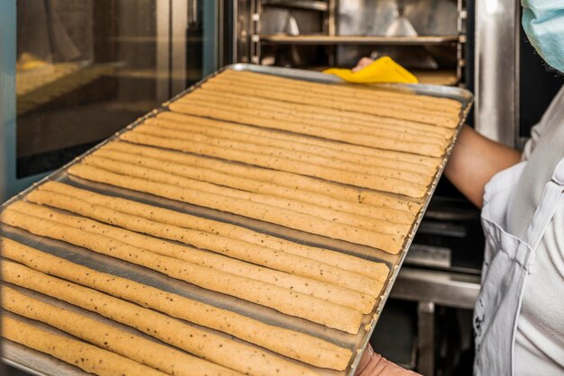 Person putting a silver with raw bread into an oven in an artisan bakery