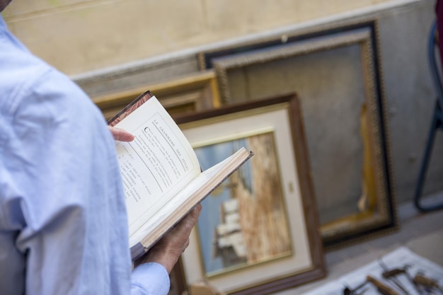 Foto una persona che legge un libro da comprare in un mercato di seconda mano