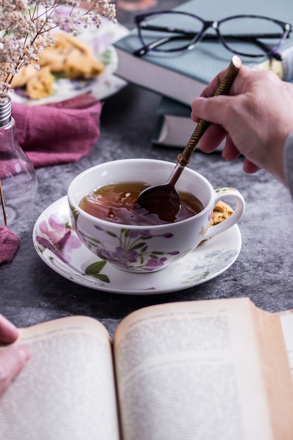 Photo a person reading a book white stirring of the tea