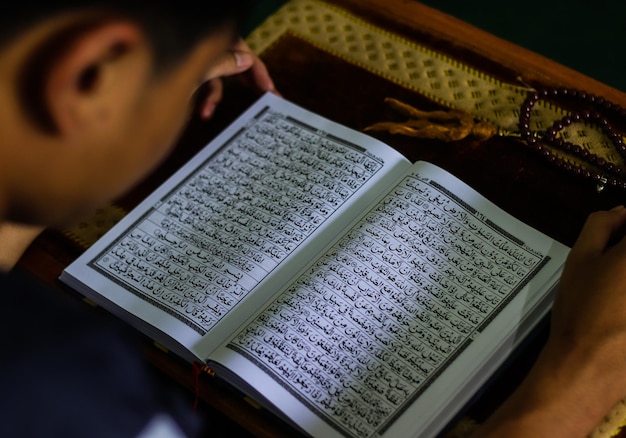 A person reading a book with the words'holy quran'on it