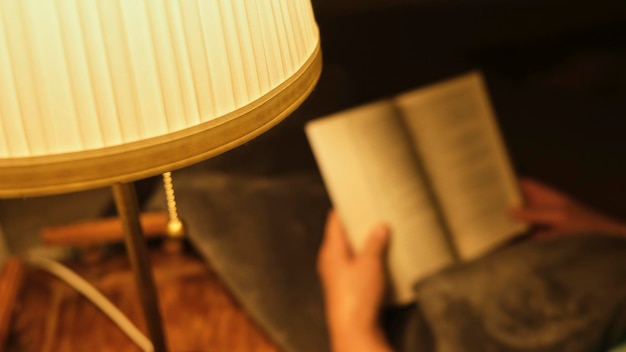 Photo person reading with the orange light of a lamp in the comfort of his home in winter