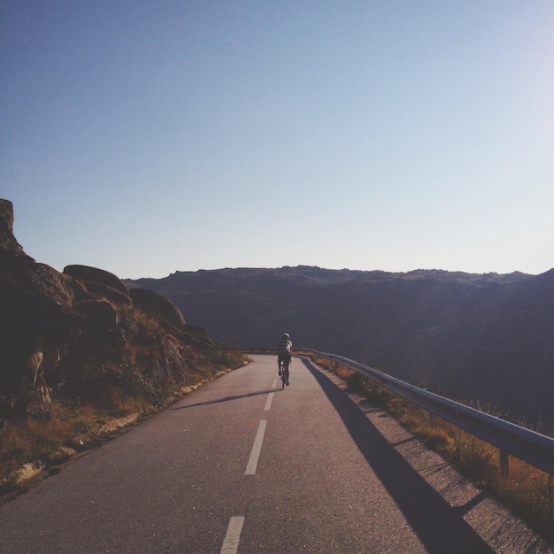 Photo person riding bicycle on mountain road against clear sky