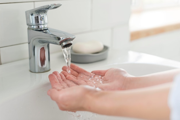 Person rinsing their hands at the sink with water