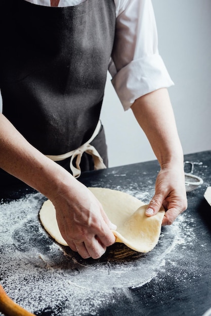 Person rolling a piece of dough with hands Vertical studio shot