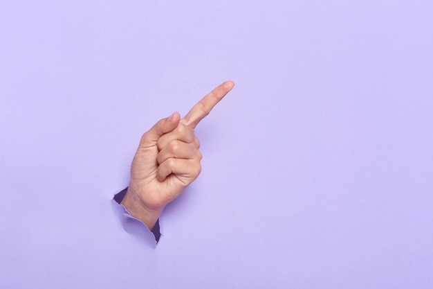 Person's hand breaking through lilac paper wall demonstrates copy space for your promotional content or discount Advertisement and proposal Background texture Banner for sales