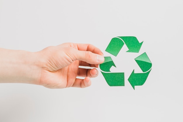 A person's hand holding green recycle icon isolated on white background