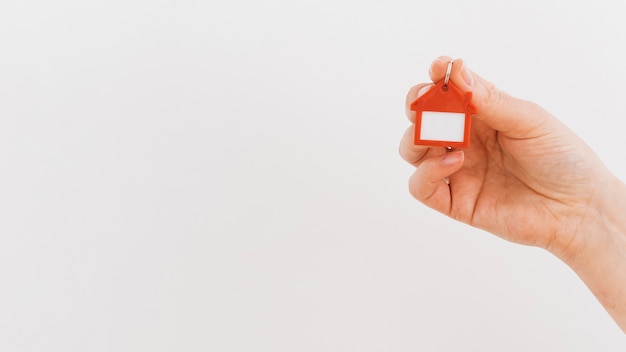 Photo a person's hand holding house keychain on white backdrop