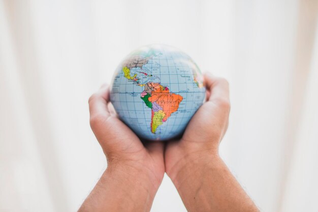 Photo person s hand holding small globe