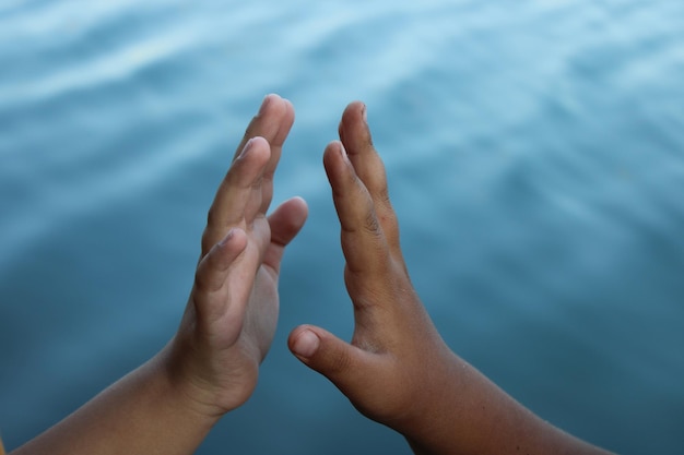 A person's hands are shown in front of a body of water.