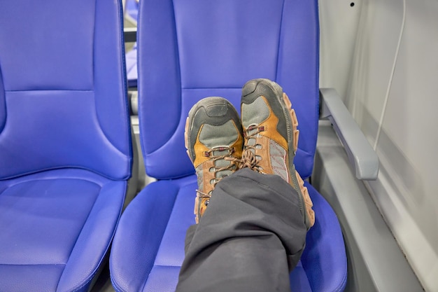 A person's legs are resting on a bus seat with blue seats.