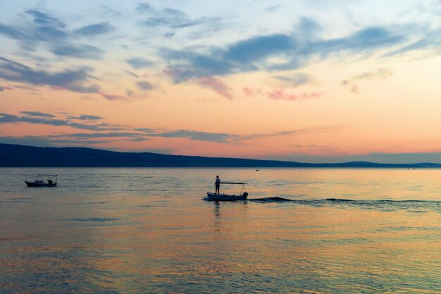 クロアチア、オミシュのアドリア海でボートに乗って航海している人。日没時に