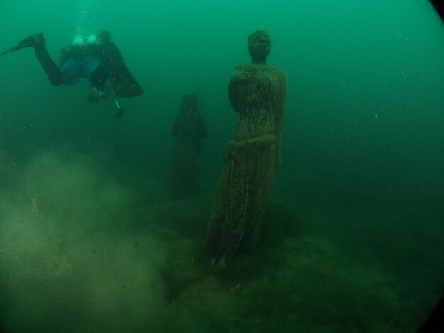 写真 海中の像のそばでスキューバダイビングをする人