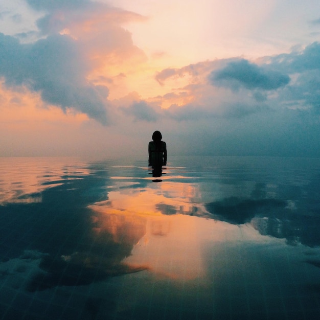 Photo person in sea at sunrise