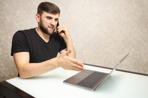 человек в самоизоляции работает дома на ноутбуке, разговаривает по телефону