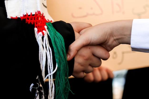 Foto una persona che stringe la mano con la scrittura araba sul muro