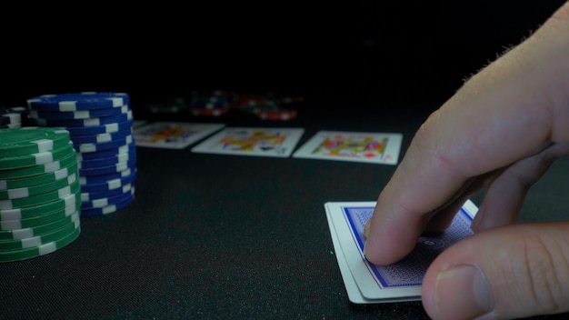 Человек, показывающий свою колоду в покерной игре Карточный игрок проверяет свою руку два туза в фишках в