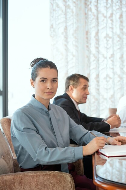 A person sitting in armchair on background of delegate having negotiation