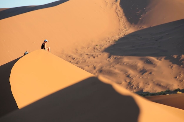 Photo person sitting on sandy desert