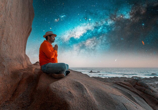 Foto persona seduta sulla cima della montagna che medita o contempla la notte stellata con lo sfondo della via latteax9