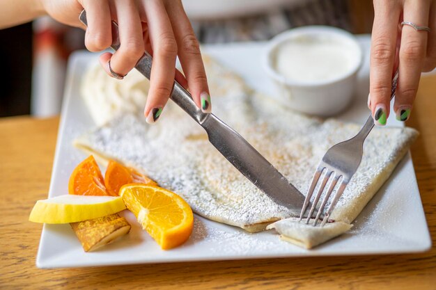 Foto persona che affetta una torta cremosa di carote e zucchero in polvere