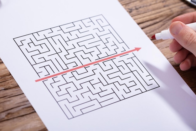 person solving maze puzzle with red marker