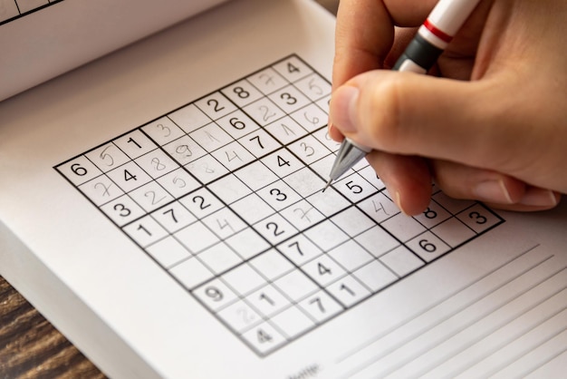 Photo person solving a sudoku puzzle on a wooden table