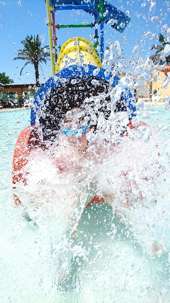 Foto persona che spruzza acqua su uno scivolo nel parco