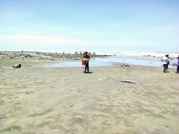 Foto una persona in piedi su una spiaggia con una tavola da surf nella sabbia.