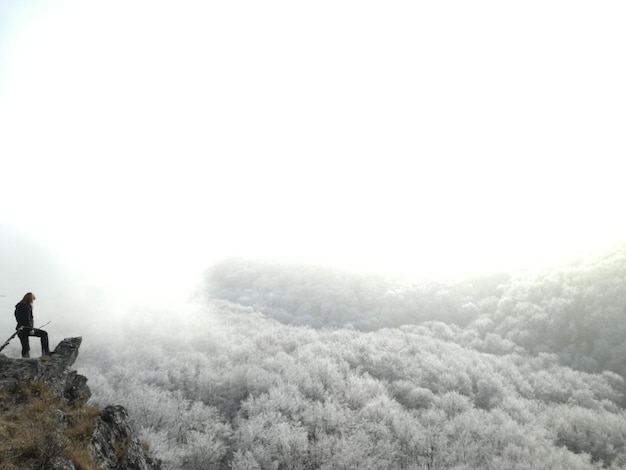 写真 冬の空に向かって崖の上に立っている人