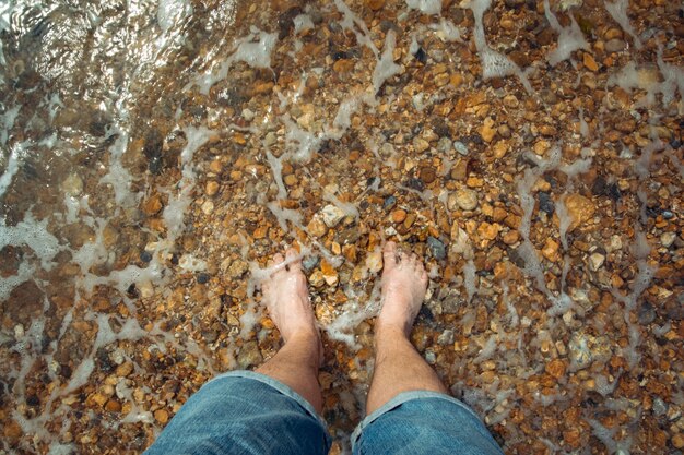 A person standing in water with their feet in the water