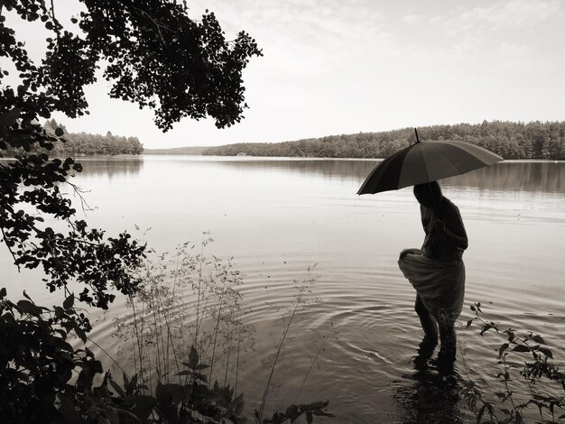 Person standing with umbrella at river