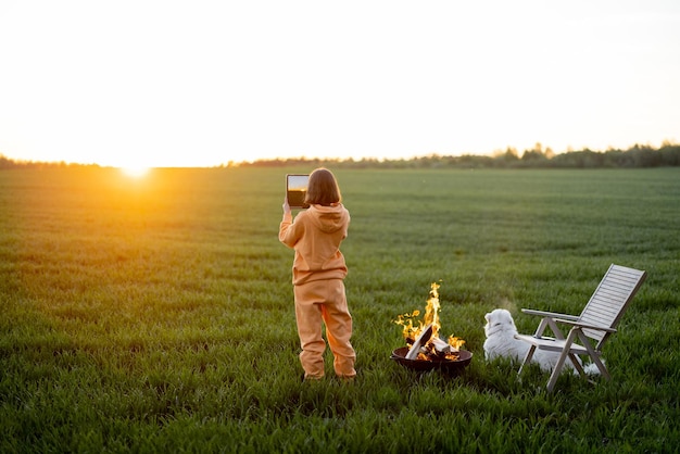 人はフィールドでリラックスしながら美しい夕日の写真を撮ります