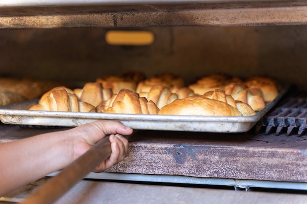 Persona che estrae i pasticcini da un forno industriale