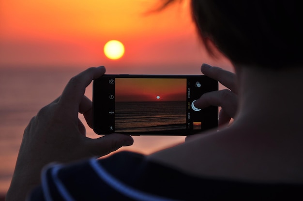 Photo person taking sunset shot on mobile