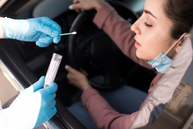 Фото Человек, проверяющий женщину в машине на коронавирус