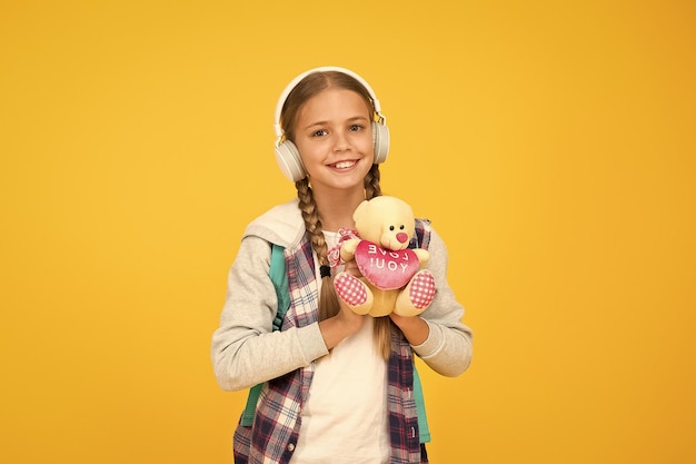 Person that cares hipster girl lpove play with toy schoolgirl casual style hold bear toy autumn time for knowledge child listen music headset childhood education and development audio book