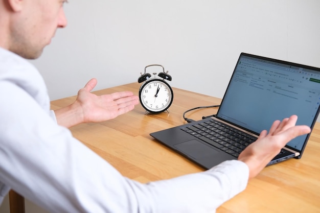 Person throws up his hands in bewilderment and stress next to laptop