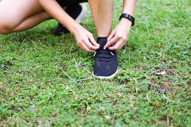 Person tie a shoe preparing getting ready for run or exercises\
on the lawn ground in the park