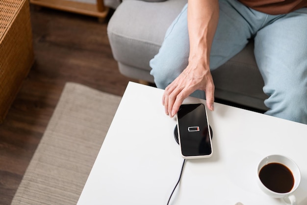 ワイヤレスバッテリー充電器でスマートフォンを充電しようとしている人