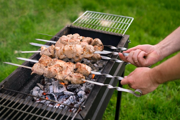 La persona gira uno spiedino con un kebab di carne nel patio