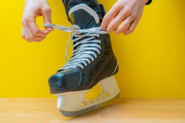 Person tying shoelaces on a skates before skating in an ice rink b