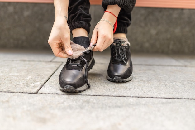 A person tying their shoes on a sidewalk.