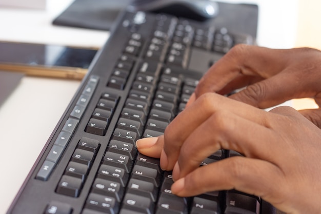 Person typing on keyboard in front of a tablet a cellphone