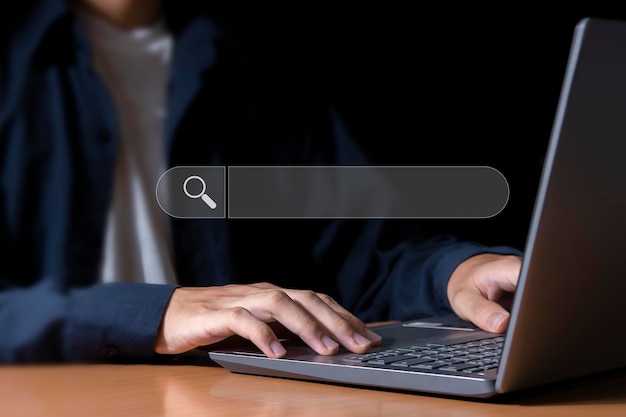 A person typing on a laptop with a search bar.