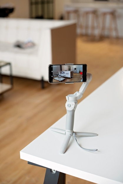 A person uses a phone with a stabilizer and takes photos and videos in real time in a modern interior.