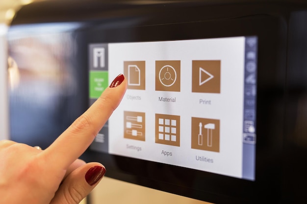 Person usin 3 D printers touchscreen