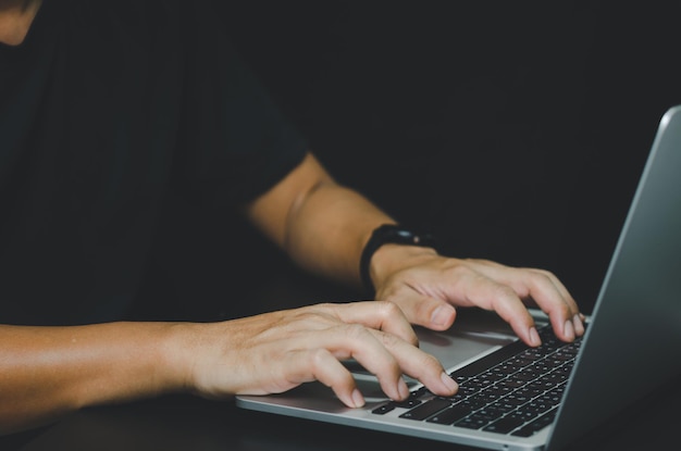 Person using in hand keyboard computer laptop on black background